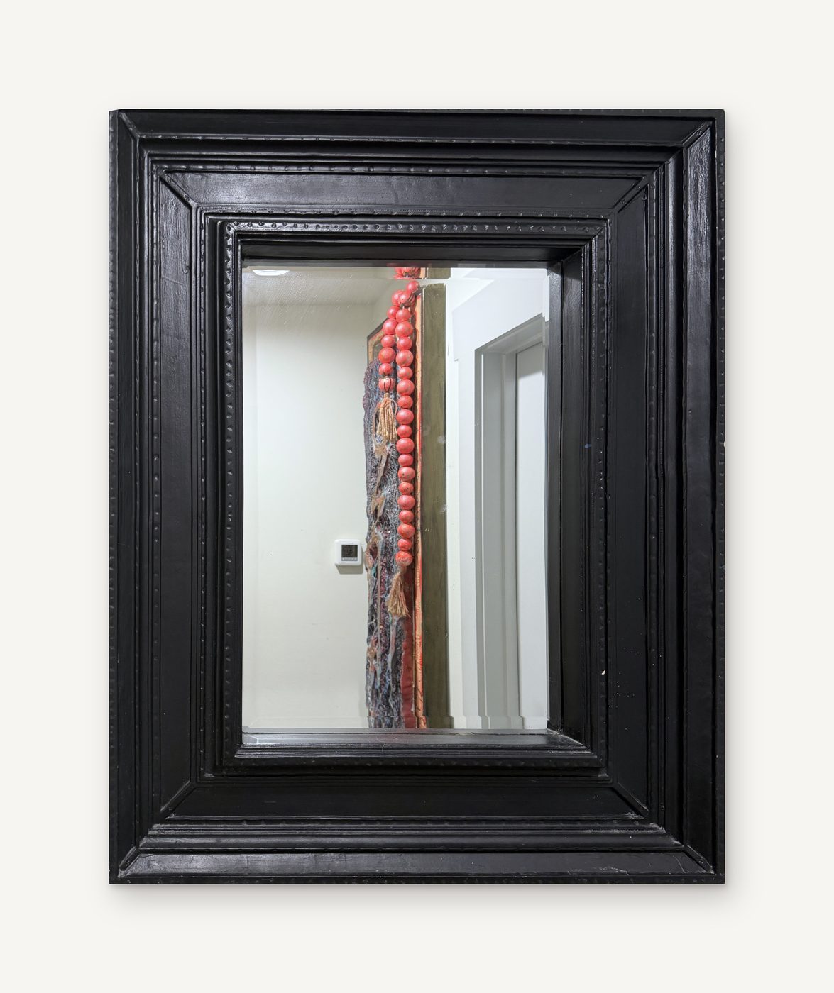 A mirror in a thick, deeply carved black wood frame