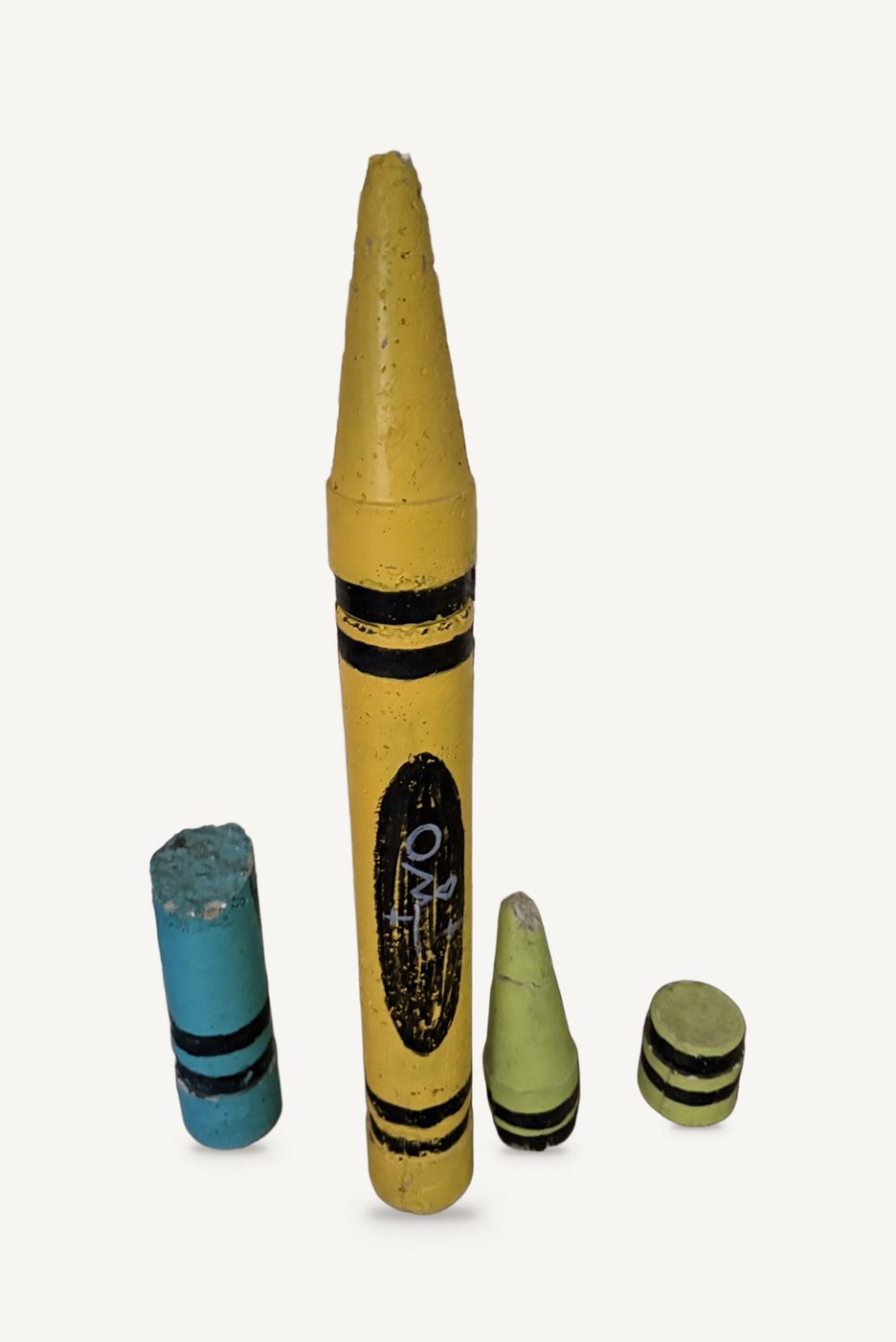 Crayons: a giant yellow cast-cement crayon with smaller blue, green and black crayons beside it