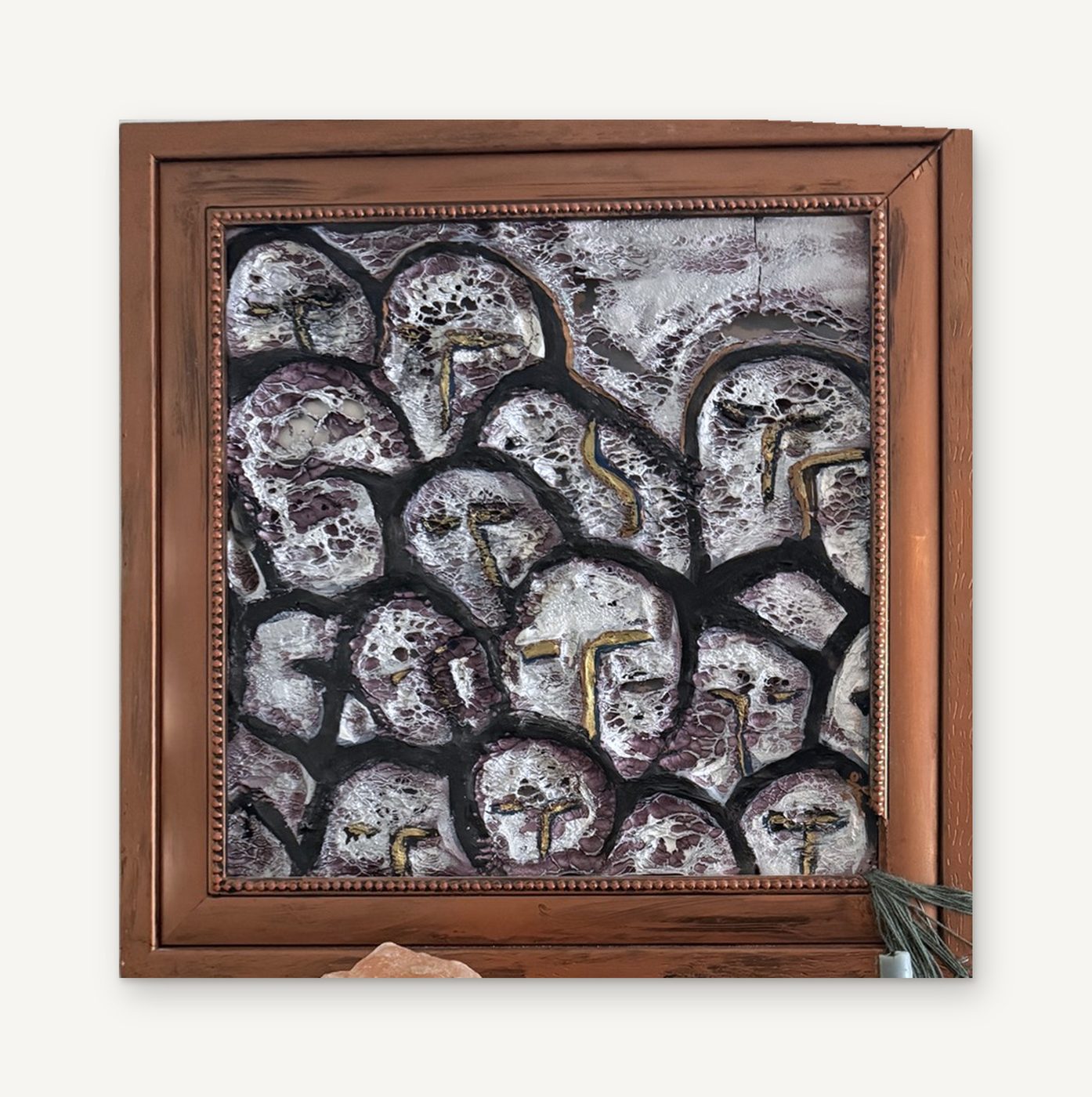 Heads II: a square relief of silver faces outlined in black, in a carved copper-toned wood frame