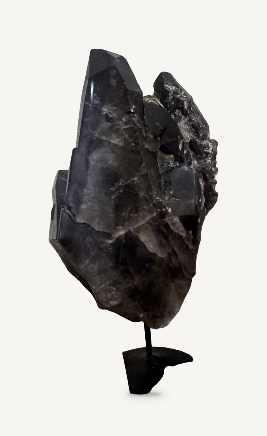 A large dark smoky quartz crystal mounted upright on a black metal stand