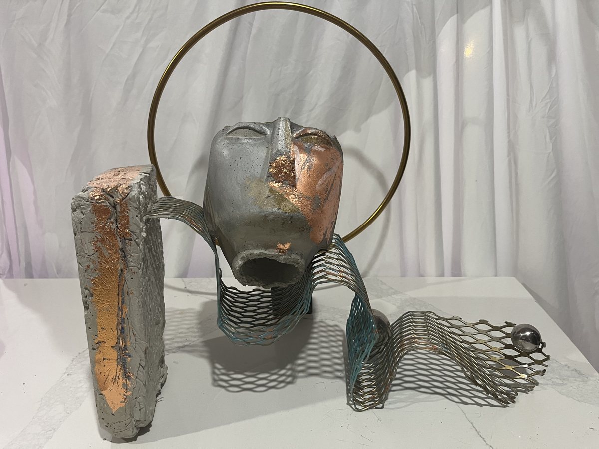The Saint: a silver and copper face inside a brass halo with a ribbon of metal mesh