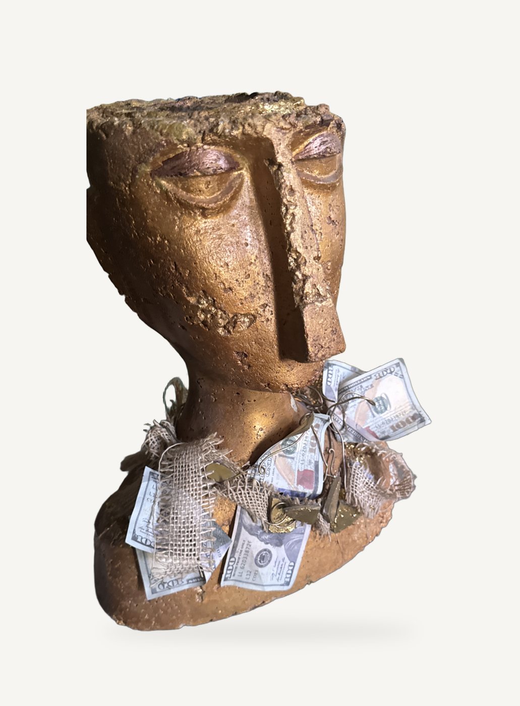 The Social Climber: a gold cast head with a long face, adorned with burlap, gold stones and a necklace of play money